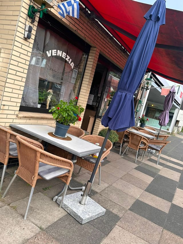 Terrasse mit Sonnenschirm vor dem Fenster mit dem Venezia-Schriftzug